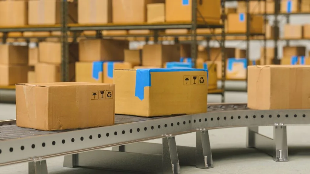Boxes on a conveyor belt in a warehouse, highlighting the importance of managing production time and potential delays in manufacturing.